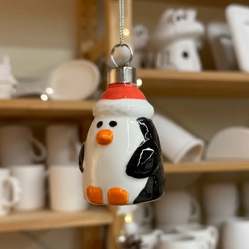 Ceramic penguin ornament with a Santa hat, hand-painted at the Triana workshop
