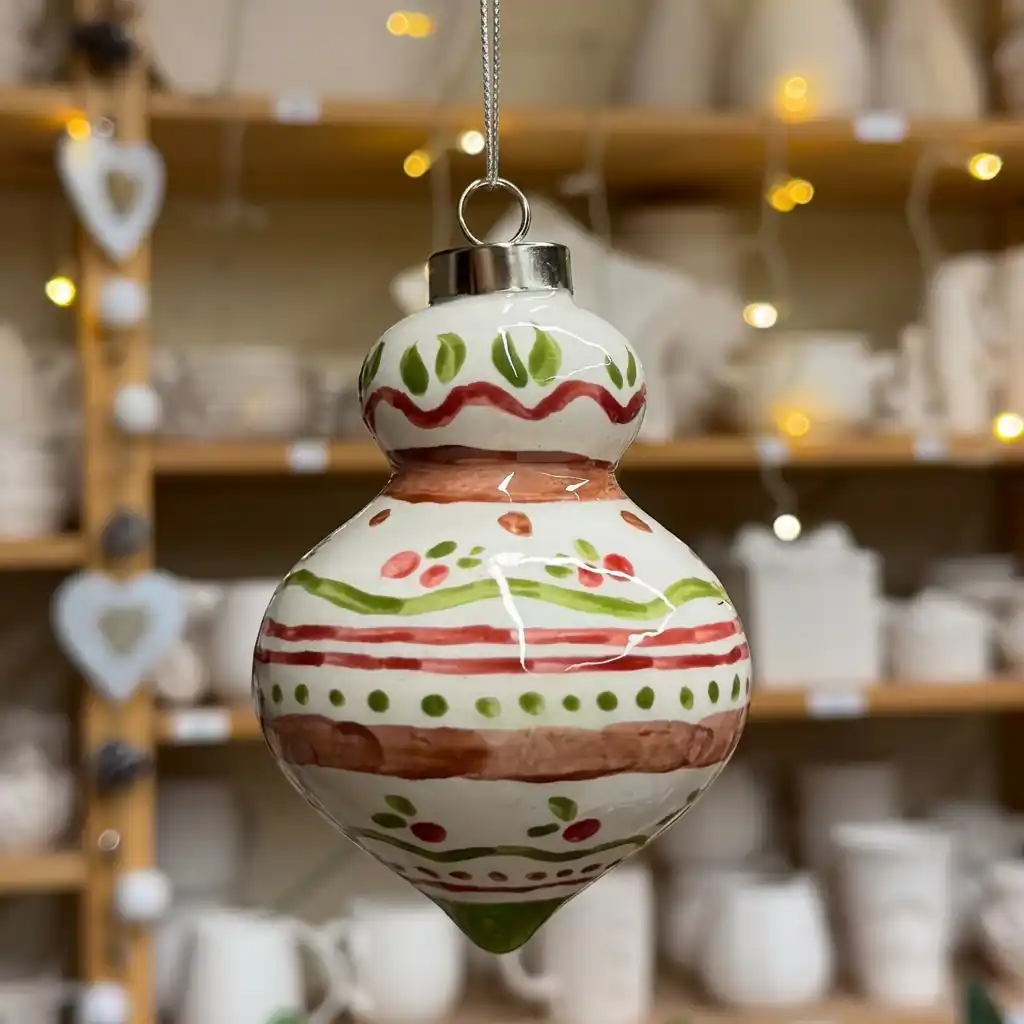 Teardrop ceramic ornament painted with red and green stripes, dots and leaves